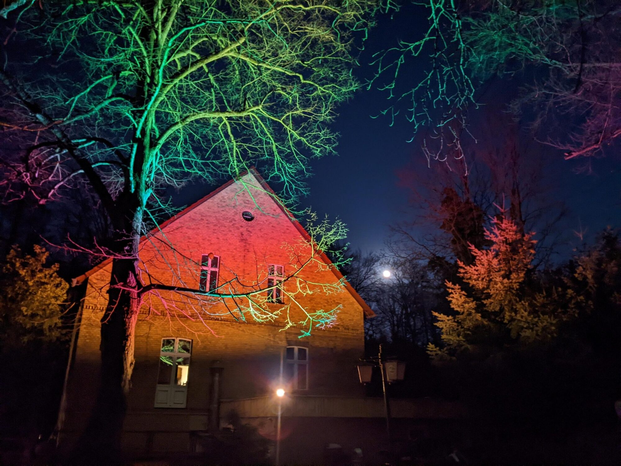 The façade of the hotel at night, lit by coloured lights